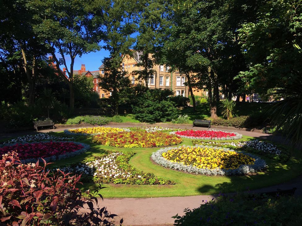 A garden with flower beds and benches at Apartment 4 in Lytham St. Annes