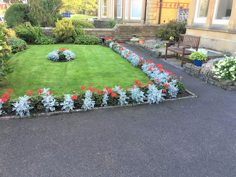 A garden with flower beds and a bench at Apartment 4 in Lytham St. Annes