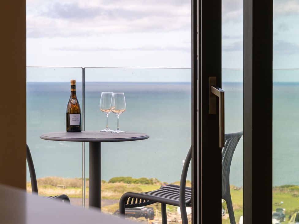 A balcony with a table and wine glasses at Clifftop House Hot Tub in St Ives
