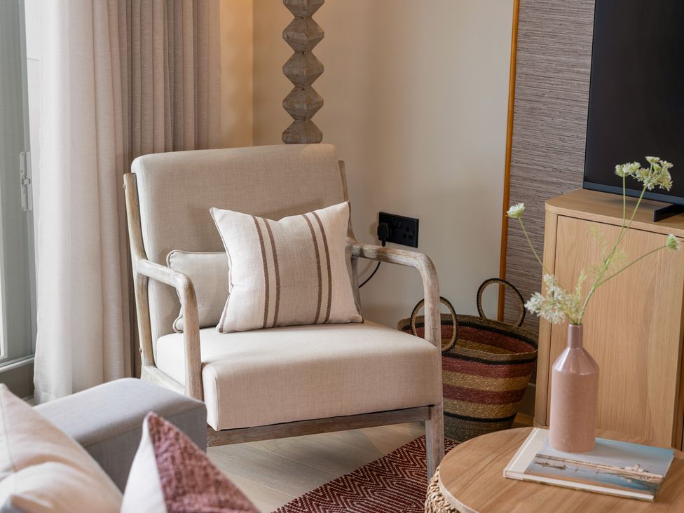 A living room with an armchair and a vase on a side table at Clifftop House Hot Tub in St Ives