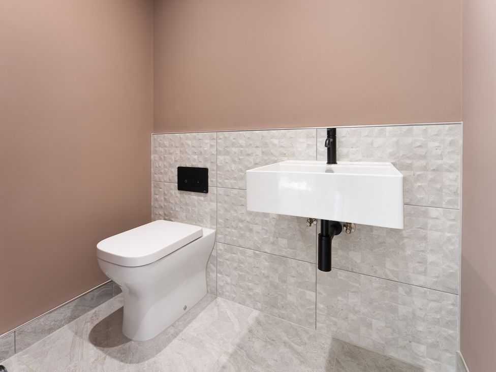 A bathroom with a toilet and a wall-mounted sink at Clifftop House Hot Tub in St Ives