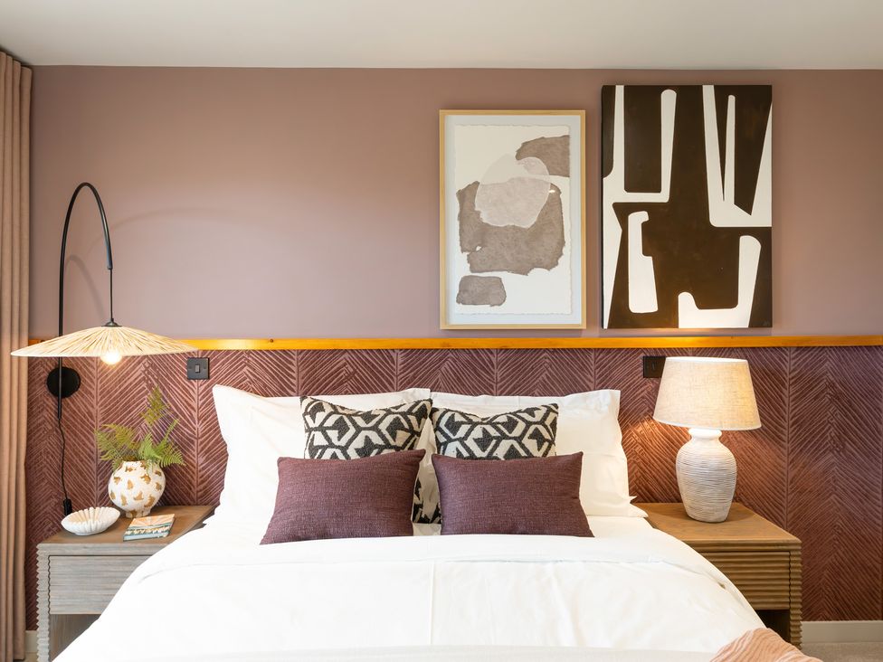 A bedroom with a bed, bedside table, lamp, and art at Clifftop House Hot Tub, St Ives