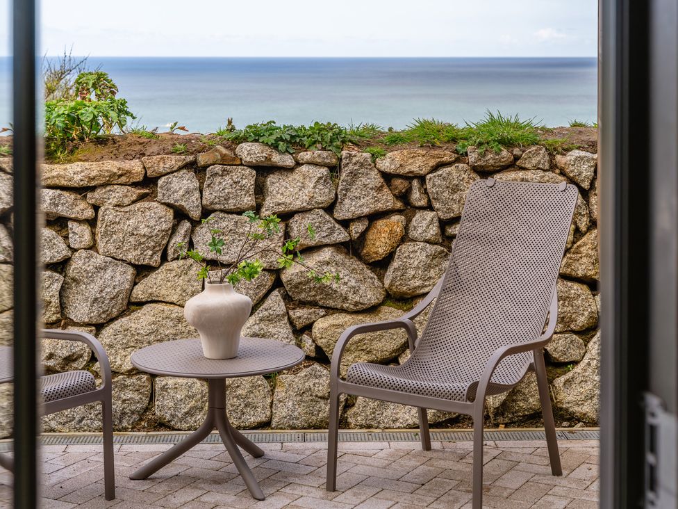 An outdoor patio with a table and chairs at Clifftop House Hot Tub in St Ives