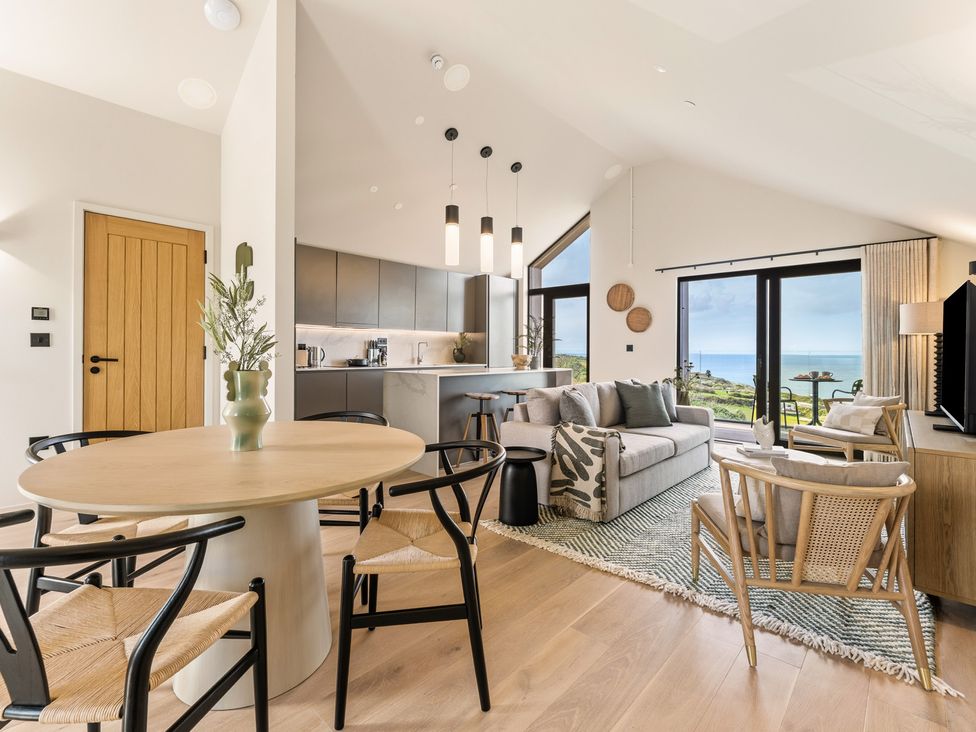 A living room with a sofa, dining table, and kitchen area at tbc in St. Ives