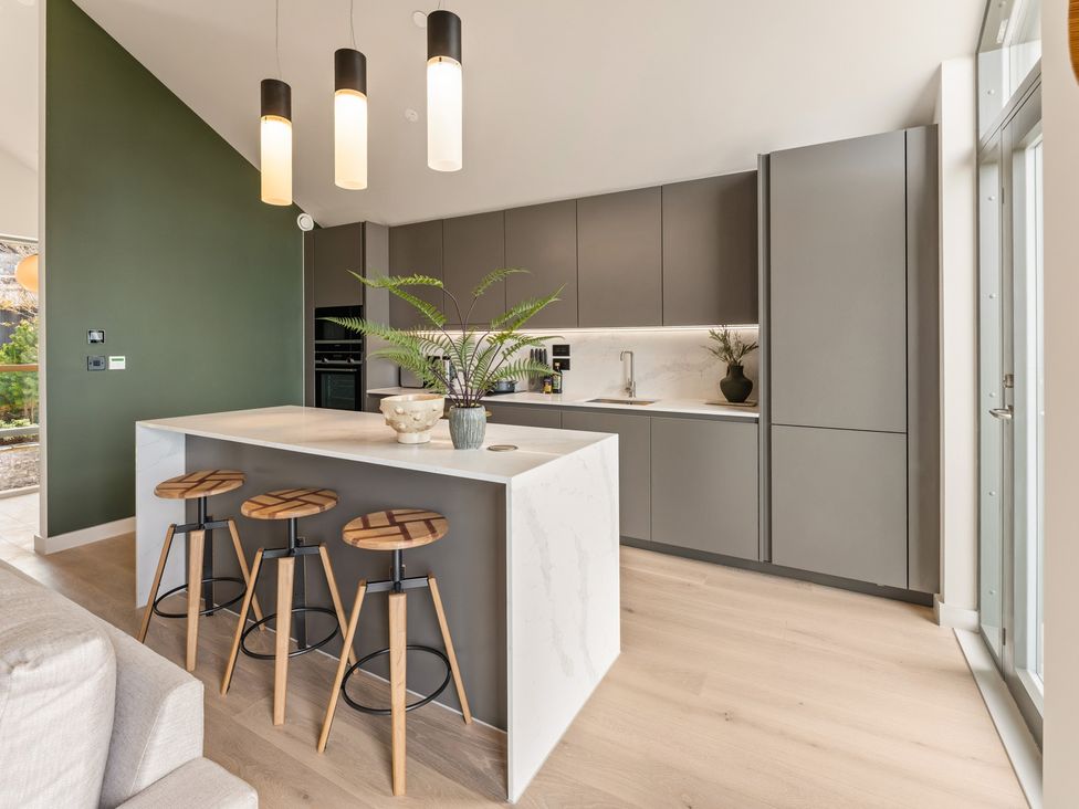A kitchen with an island and bar stools at tbc in St. Ives