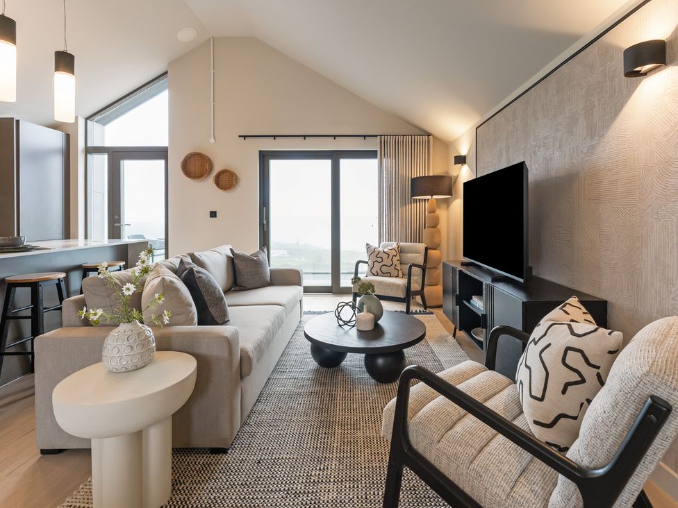 A living room with a sofa, armchairs, coffee table and television at tbc in St. Ives