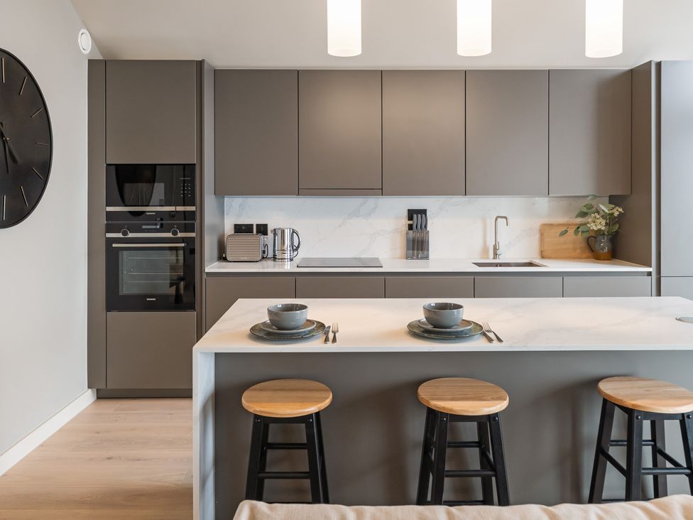 A kitchen with cabinets, appliances and bar stools at tbc in St. Ives