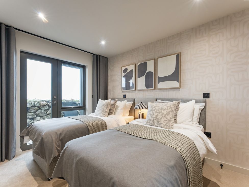 A bedroom with two beds and decorative wall art at tbc in St. Ives