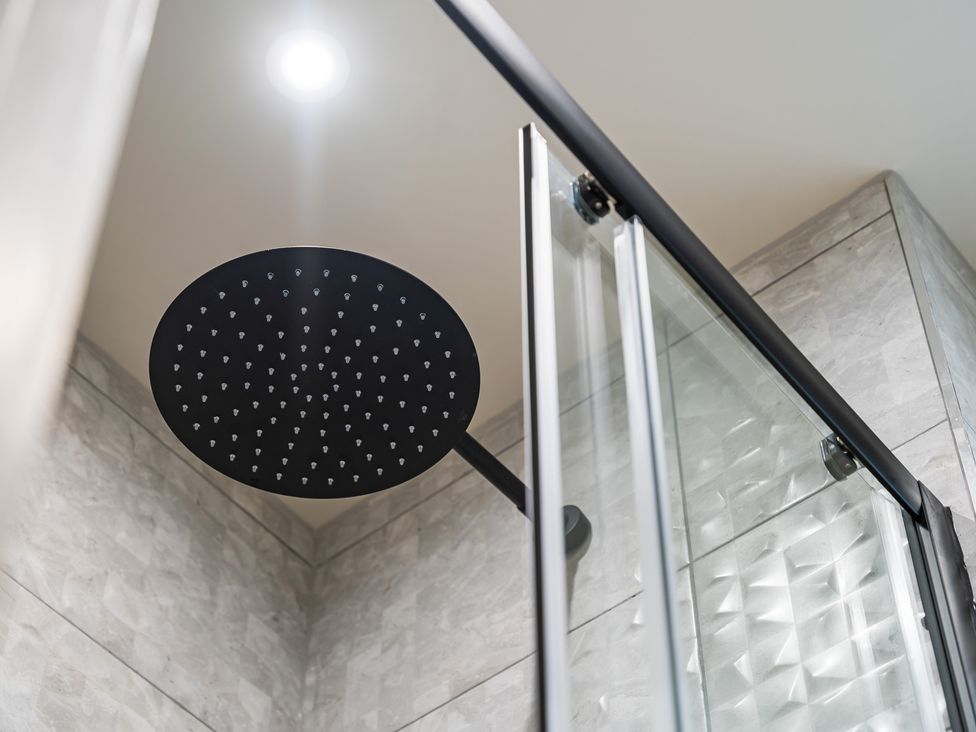 A shower area with a round shower head and glass door at tbc in St. Ives