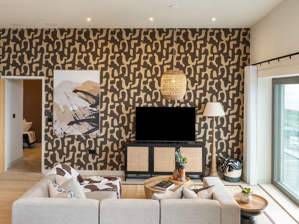 A living room with a sofa, coffee table, and television stand at tbc in St. Ives