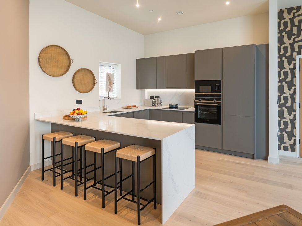 A kitchen with a countertop and bar stools at The Old Barn in St. Ives