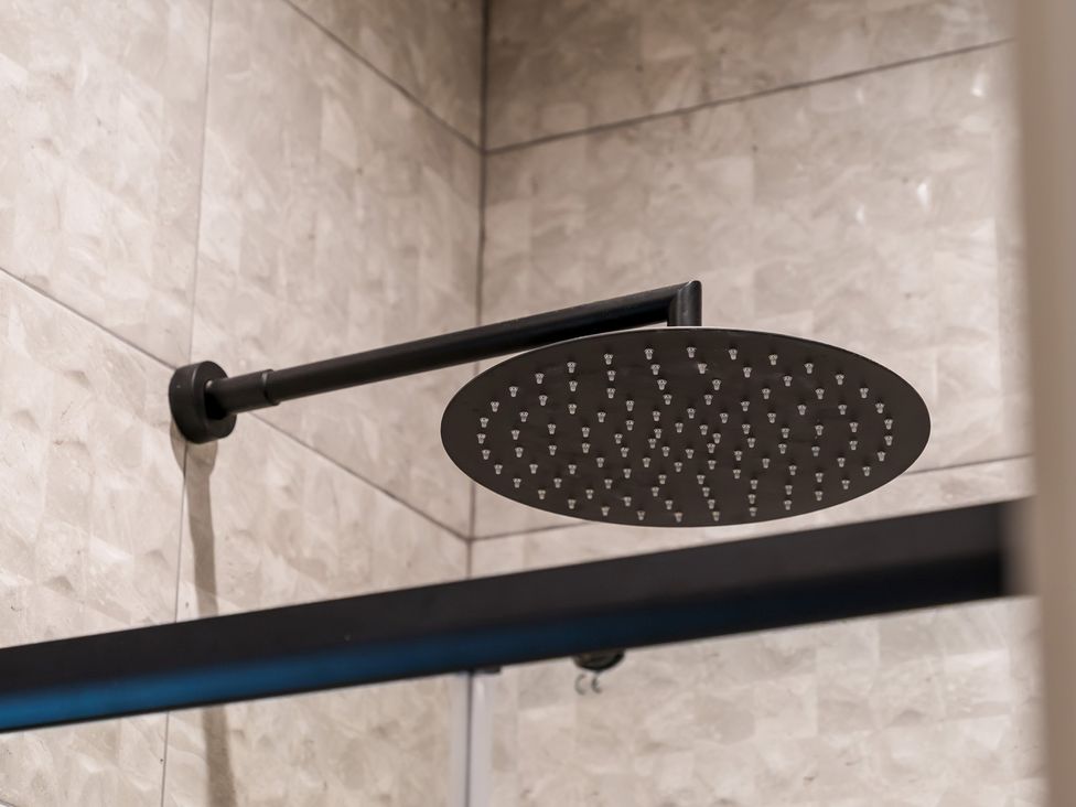 A shower head mounted on tiles at tbc St. Ives