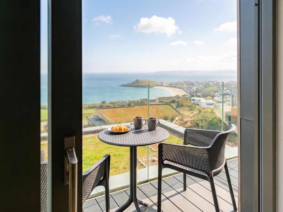 A balcony with a table and chairs overlooking the sea at Hidden 9 – Grand Bay Suite Hot Tub, St Ive