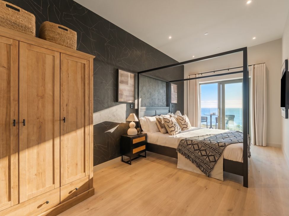 A bedroom with a bed and wardrobe at Hidden 9 – Grand Bay Suite Hot Tub in St Ive