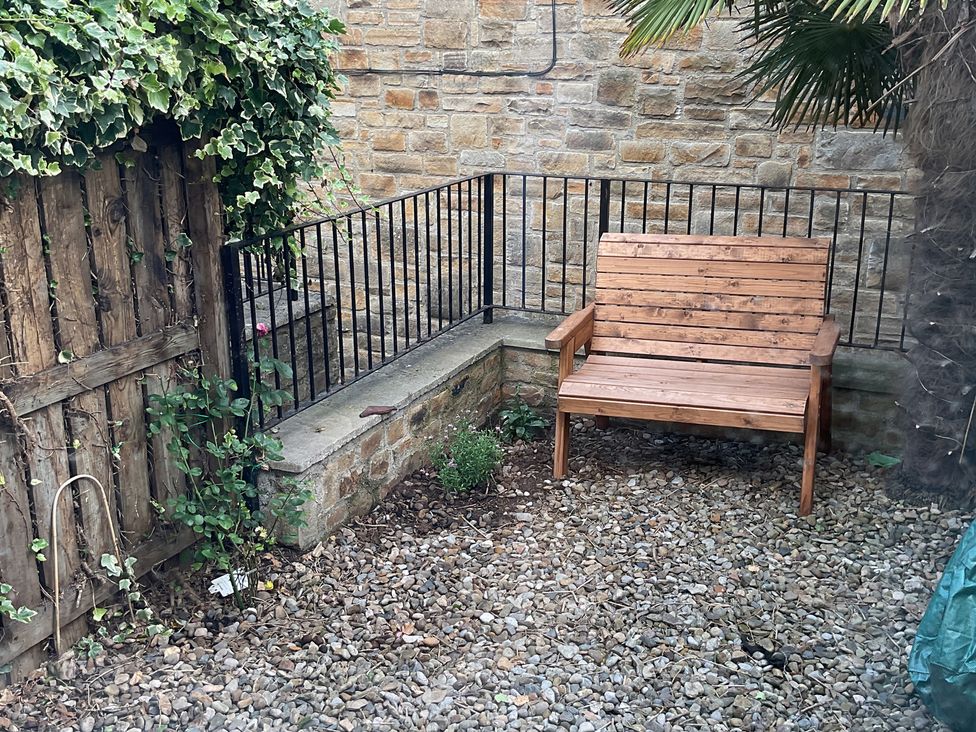 A garden with a wooden bench and a stone wall at 2 West View in Richmond