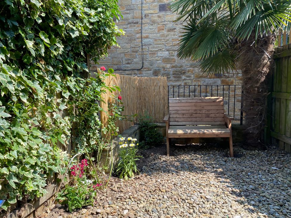 A garden with a bench, palm tree, and flowers at 2 West View Richmond