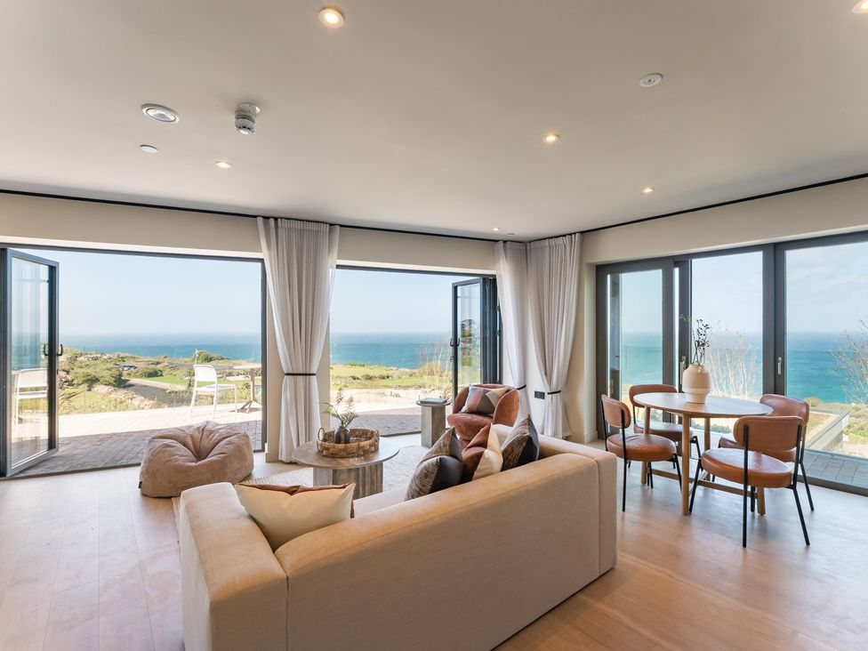 A living room with a sofa and table overlooking the ocean at tbc in St. Ives