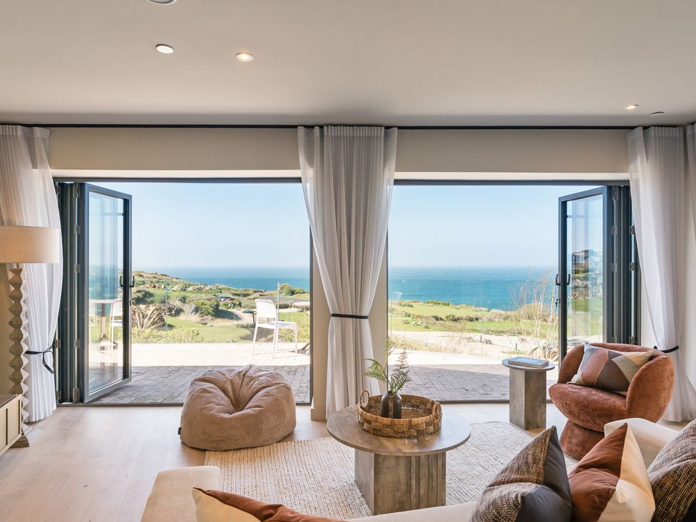 A living room with a coffee table and sofa overlooking the ocean at tbc St. Ives
