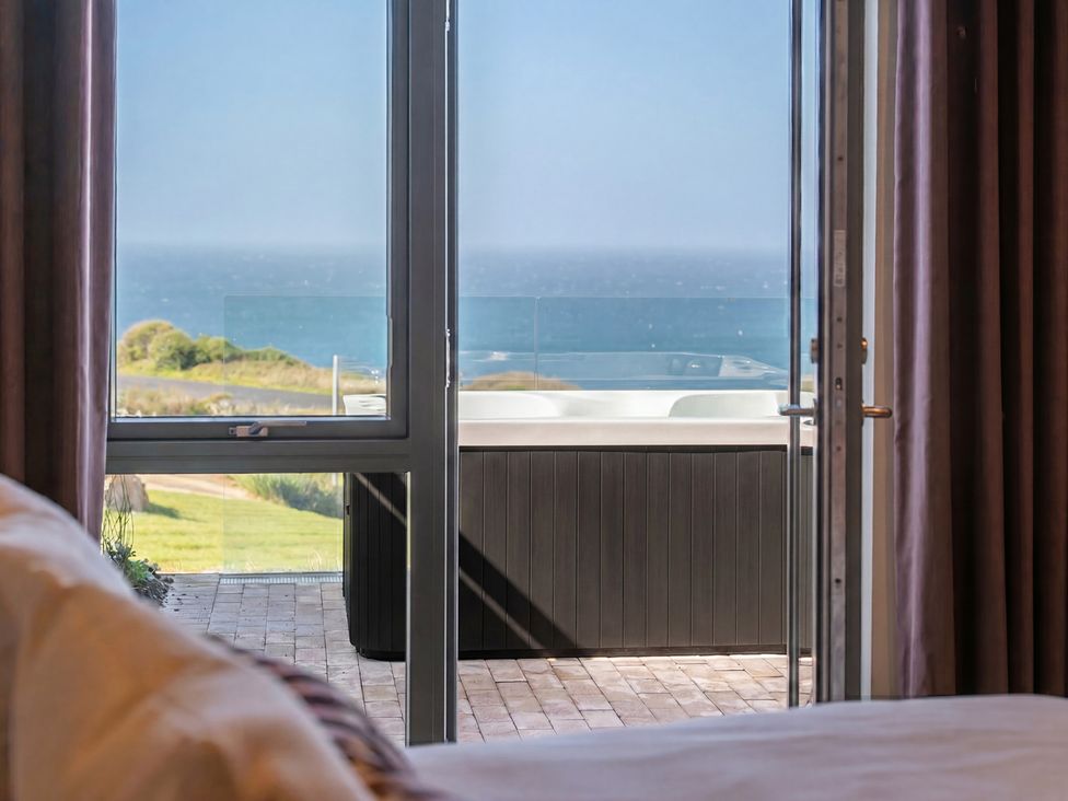 A bedroom with a view of the ocean and a spa at tbc St. Ives