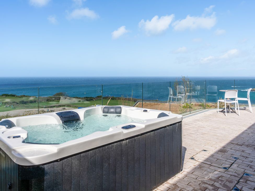 An outdoor space with a hot tub and chairs overlooking the ocean at tbc in St. Ives