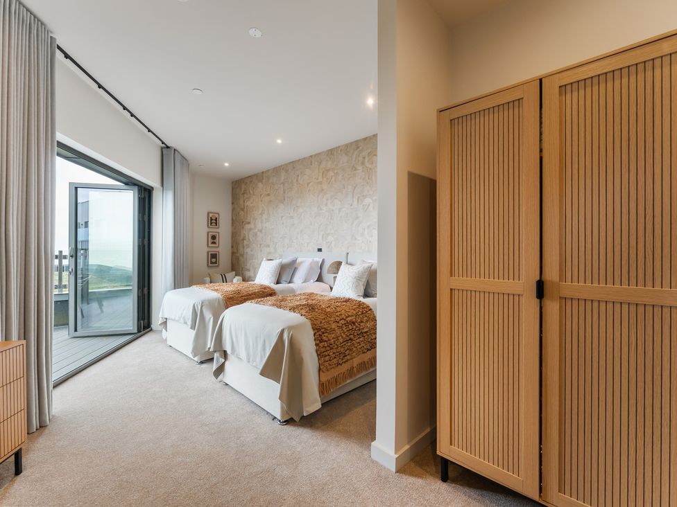 A bedroom with two beds and a wardrobe at tbc in St. Ives