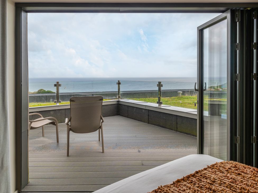 A bedroom with a view of the ocean and a chair at tbc in St. Ives