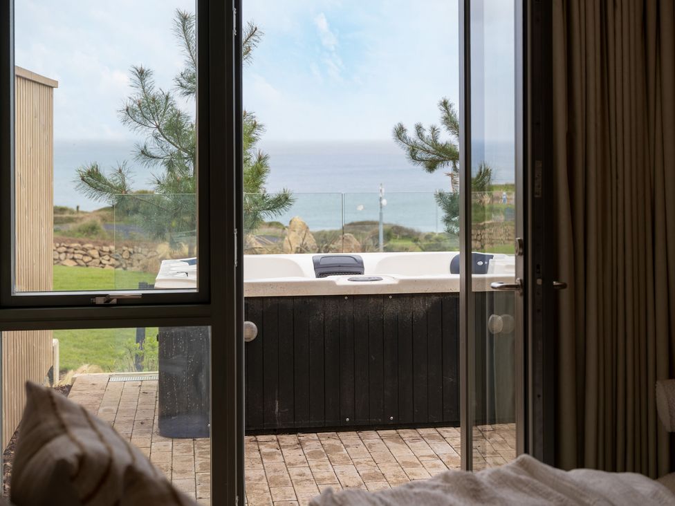 An outdoor area with a hot tub visible through a glass door at tbc in St. Ives