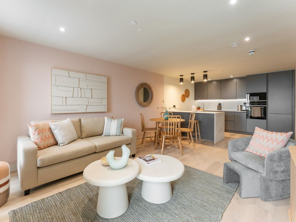 A living room with a sofa, armchair, and dining area at tbc in St. Ives