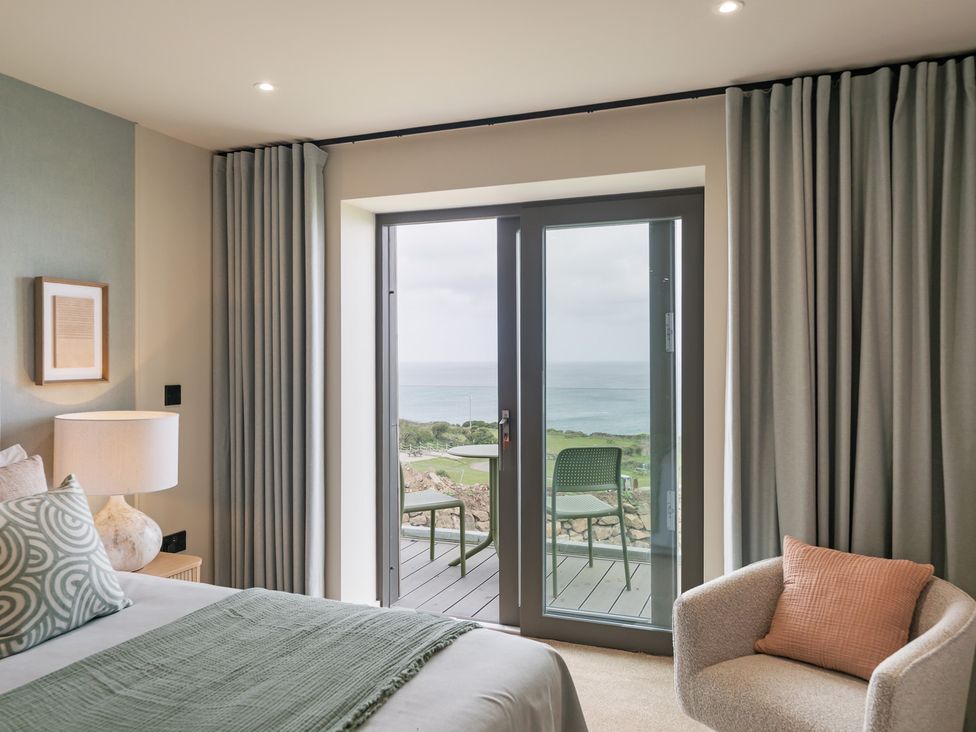 A bedroom with a bed and door opening to a view at tbc in St. Ives