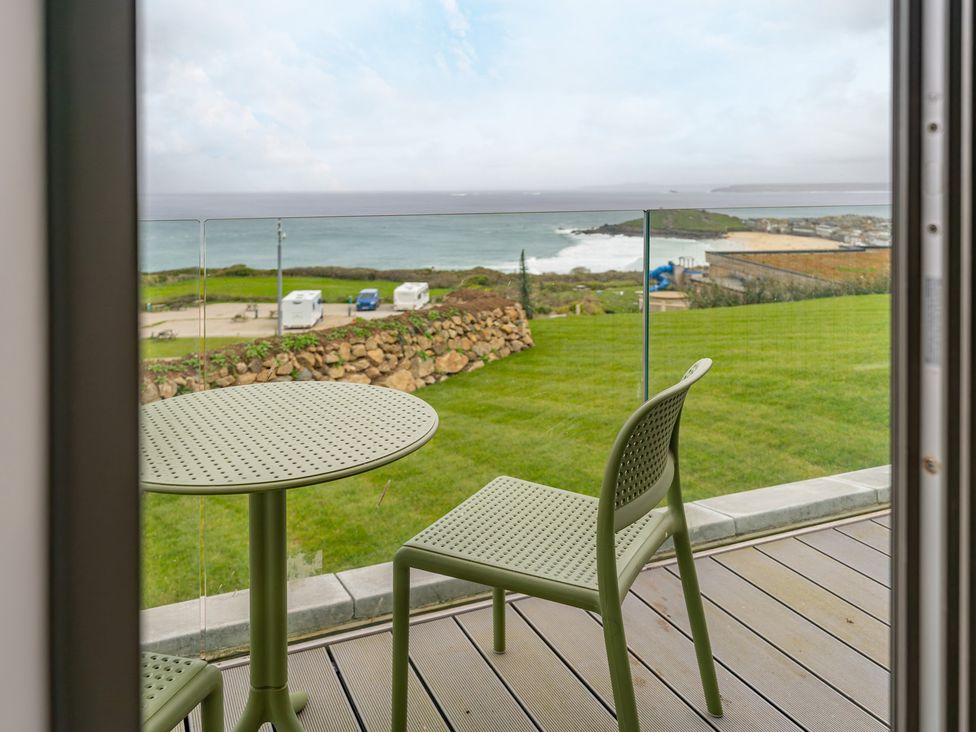 A balcony with a table and chair overlooking the ocean at tbc St. Ives
