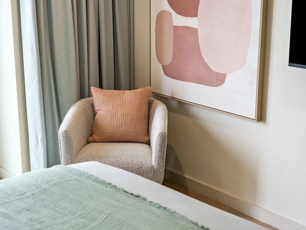 A bedroom with an armchair and wall art at tbc in St. Ives