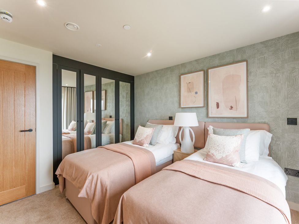 A bedroom with two beds and a bedside table at The Old Barn in St. Ives