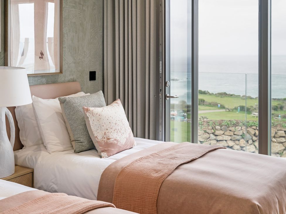 A bedroom with two beds and a window overlooking the ocean at tbc St. Ives
