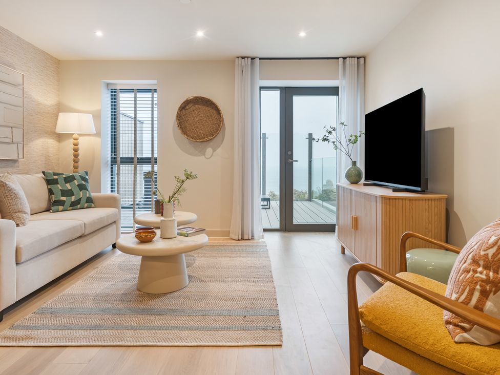 A living room with sofa, coffee table and television at Hidden 19- Coastal Hot Tub, St Ives