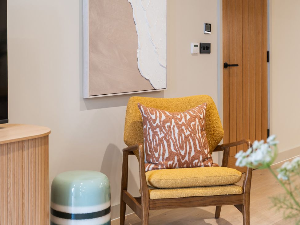 A living room with a chair and artwork at Hidden 19- Coastal Hot Tub St Ives