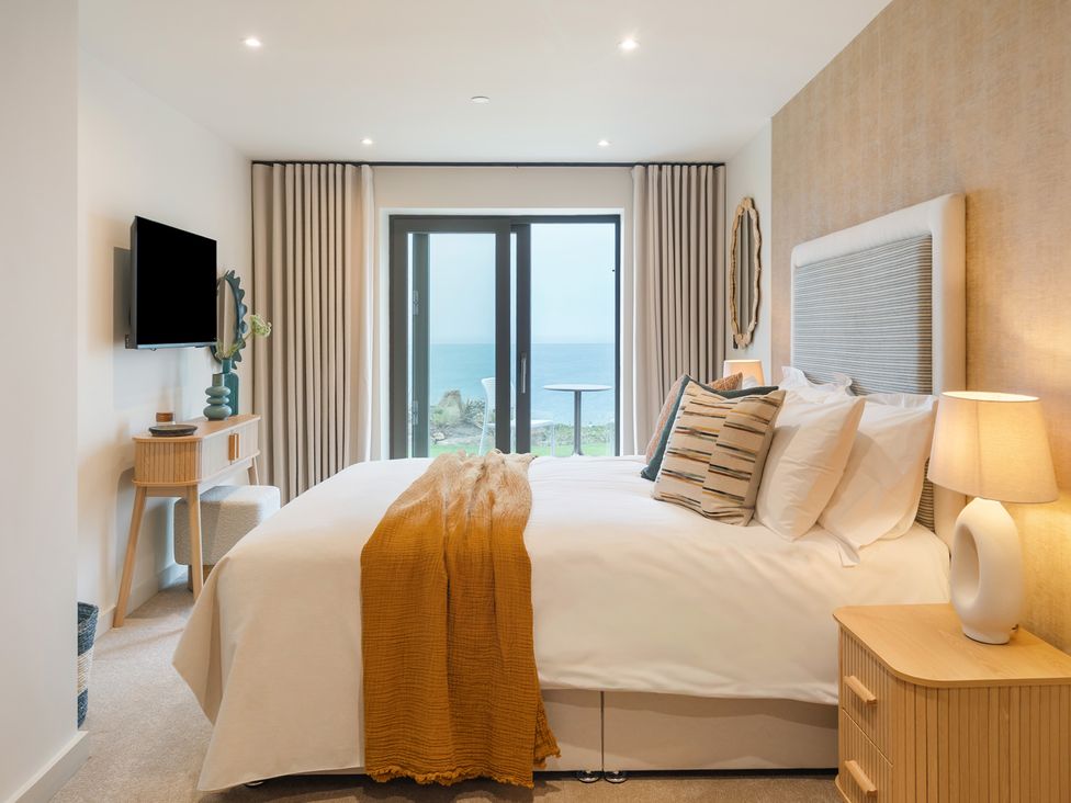A bedroom with a bed and television at Hidden 19- Coastal Hot Tub in St Ives