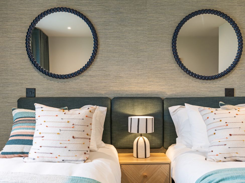 A bedroom with two beds, pillows, a lamp, and mirrors at Hidden 19- Coastal Hot Tub in St Ives
