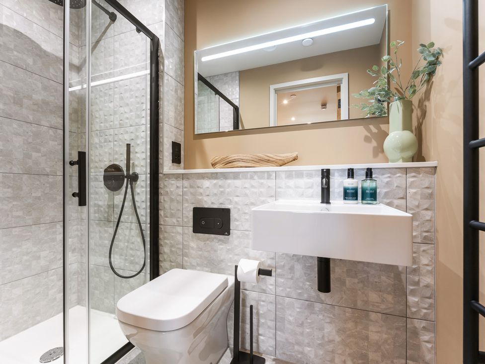 A bathroom with a shower, toilet, and sink at Hidden 19- Coastal Hot Tub in St Ives