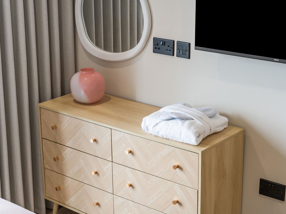 A bedroom with a dresser and mirror at The Old Barn in St. Ives