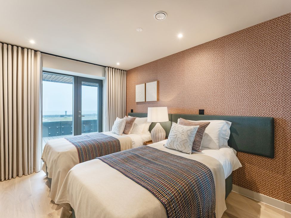 A bedroom with twin beds and a balcony door at tbc in St. Ives