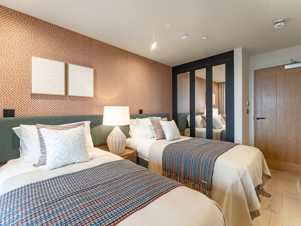 A bedroom with two beds and a wardrobe at tbc in St. Ives