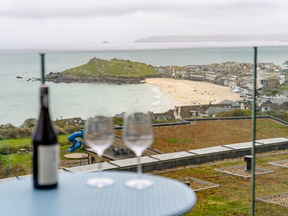 A coastal view with wine glasses and a bottle at tbc St. Ives