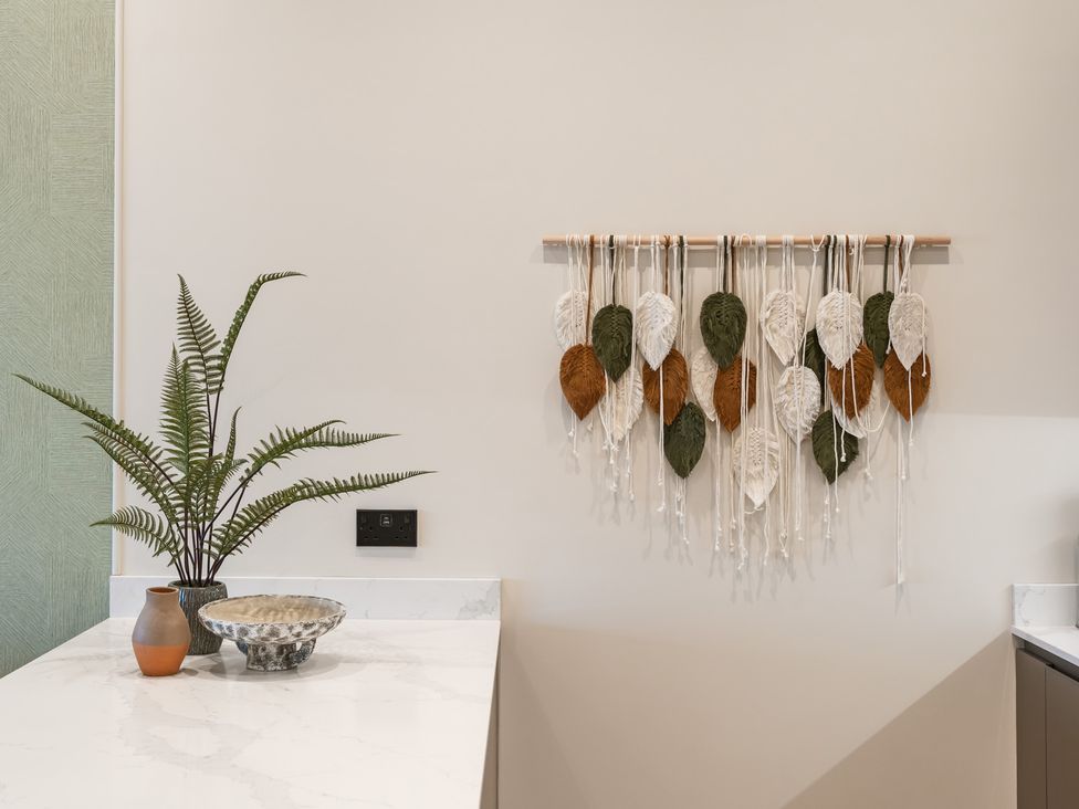 A kitchen with a decorative wall hanging and plants at tbc, St. Ives