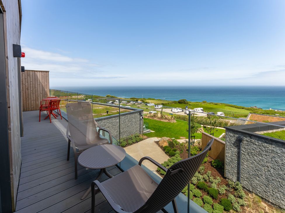 An outdoor balcony with chairs and a table overlooking the ocean at Hidden 10- Godrevy View St Ives
