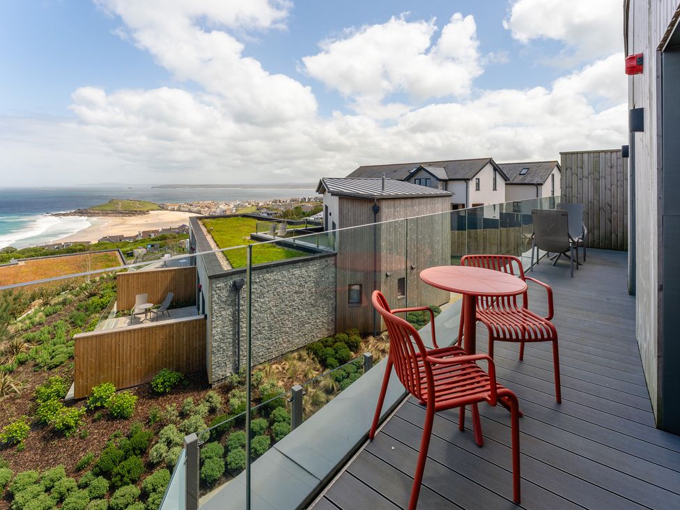 An outdoor area with a deck and chairs at Hidden 10- Godrevy View St Ives