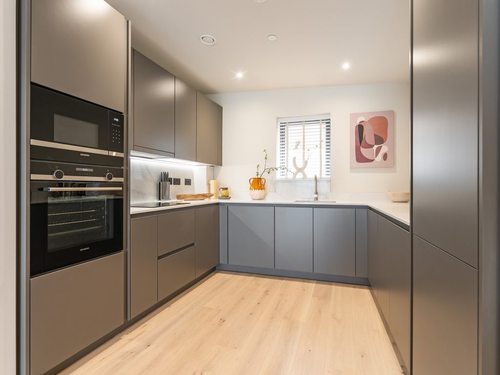 A kitchen with an oven, microwave, and kitchen cabinets at Hidden 10- Godrevy View in St Ives