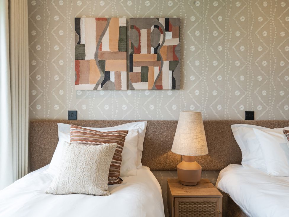A bedroom with two beds and artwork on the wall at Hidden 10- Godrevy View, St Ives