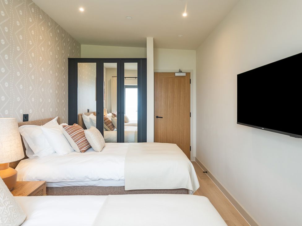 A bedroom with two beds and a television at Hidden 10- Godrevy View St Ives