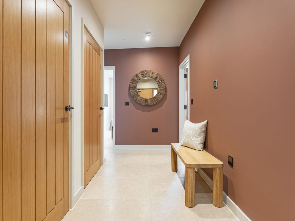 A hallway with a mirror and a bench at Hidden 10- Godrevy View St Ives