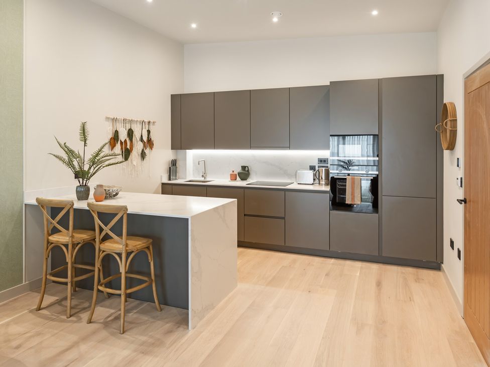 A kitchen with a counter and bar stools at tbc in St. Ives